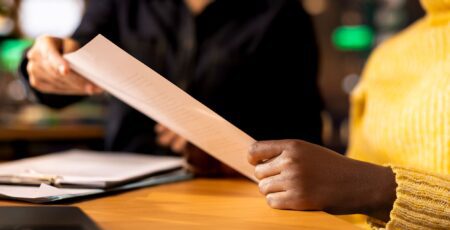 Close-up of an African American's hand receiving a paper document.